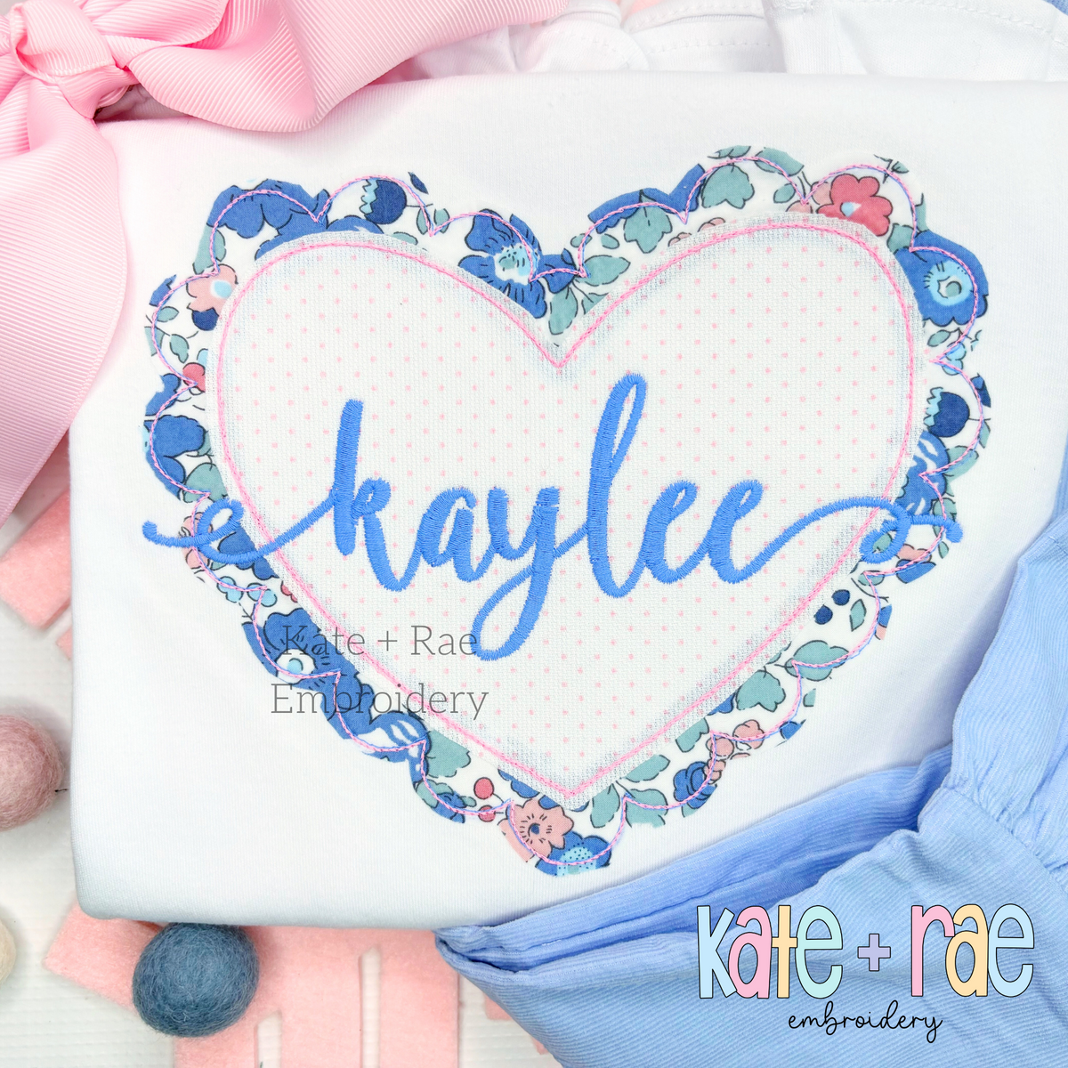 Scalloped Double Heart Bean Stitch Applique Embroidery Design: Blue floral scalloped heart applique with the name kaylee in blue script on a white shirt
