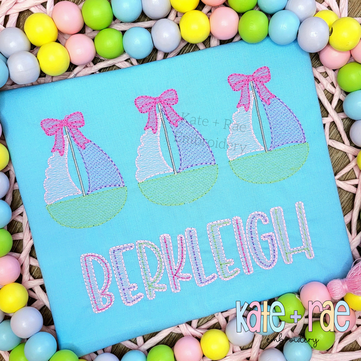 Sailboat Trio with Bows Sketch Stitch Embroidery Design: Three sketch sailboats with pink bows above the name Berkleigh on a light blue shirt
