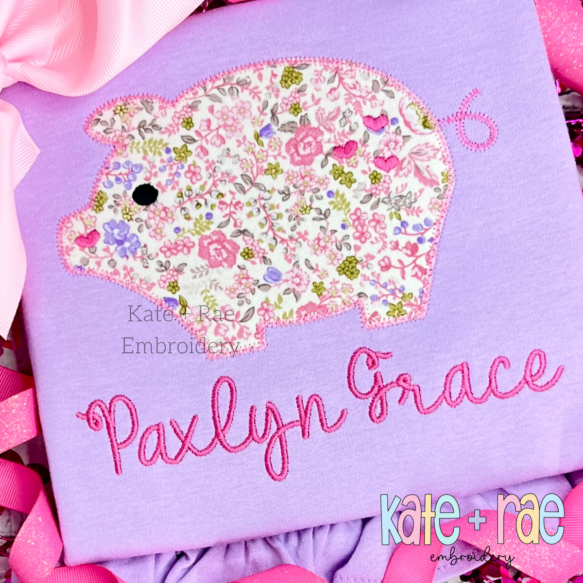 Heart Piggy Zigzag Stitch Applique Embroidery Design: Floral pig applique with hearts above the name Paxlyn Grace in pink script on a lavender shirt