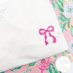 Merritt Bow MINI Cross Stitch Embroidery Design: Small pink cross stitch bow on a white tee