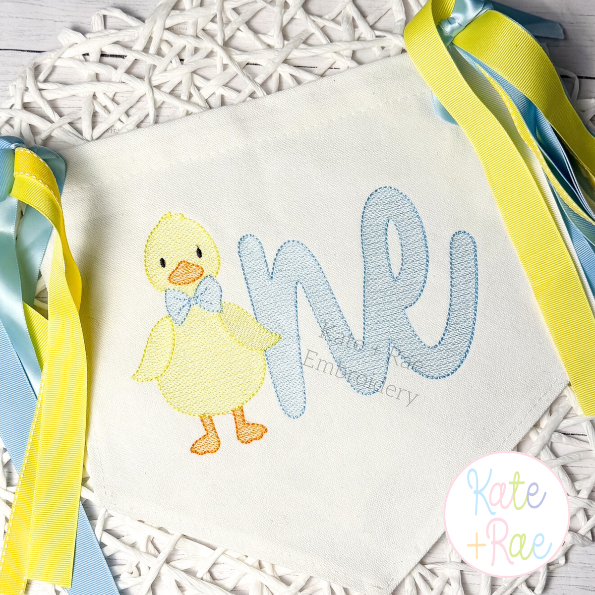 Boys One Lucky Duck with Bow Tie #2 Sketch Stitch Embroidery Design: Yellow sketch duck with a blue bow tie beside one in blue script on a pennant banner with ribbons