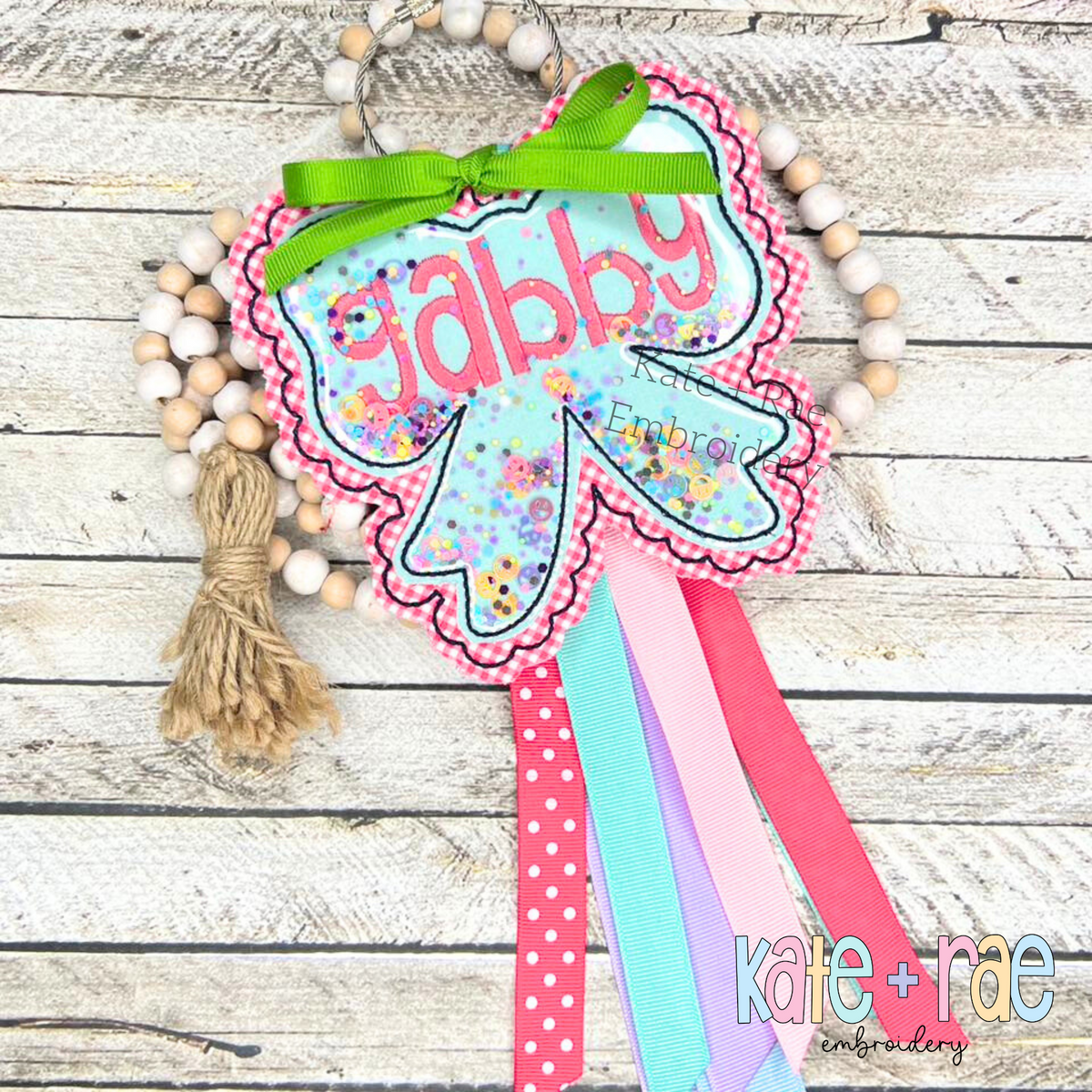 ITH Scalloped Bow Bag Tag Double Bean Stitch Applique Embroidery Design: Pink scalloped bow bag tag with a confetti shaker window and the name gabby tied with ribbons