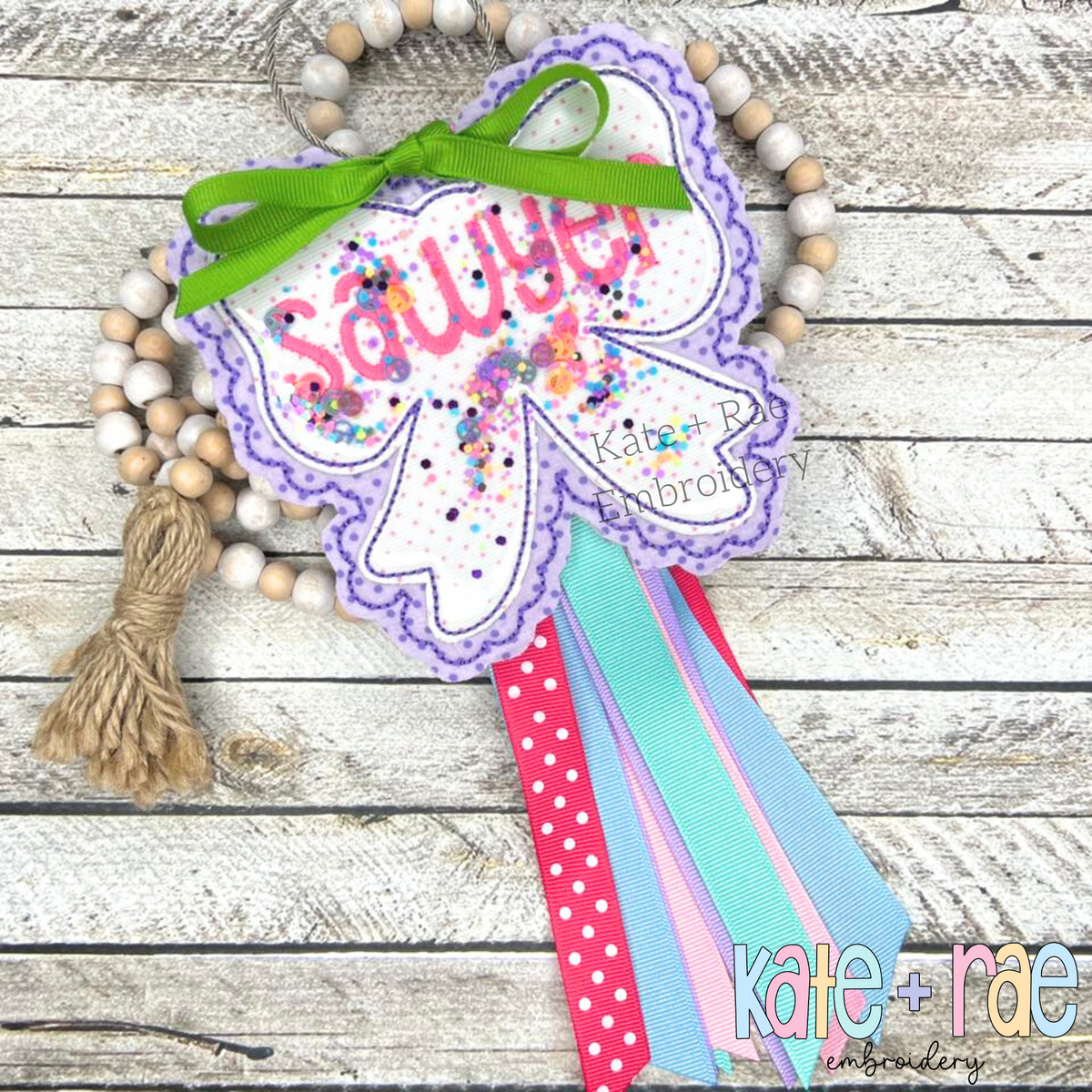 ITH Scalloped Bow Bag Tag Double Bean Stitch Applique Embroidery Design: Lavender scalloped bow bag tag with confetti shaker window and the name Sawyer tied with ribbons