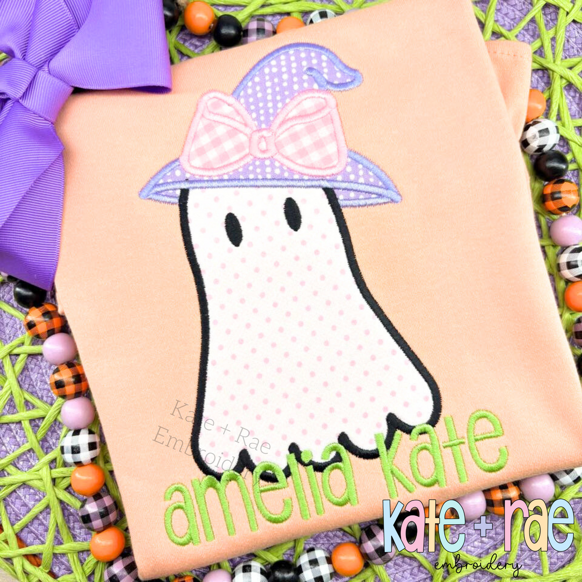 Girls Ghost with Witch Hat Satin Stitch Applique Embroidery Design: Polka dot ghost applique with a lavender witch hat and pink bow above the name amelia kate in green on a peach shirt