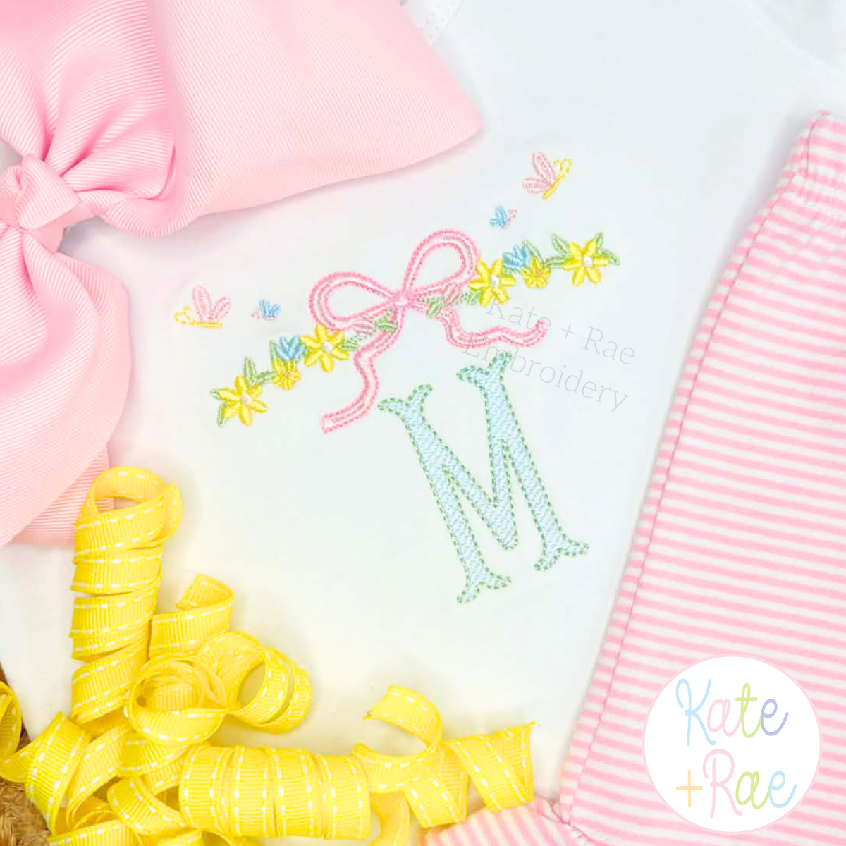 Floral Bow Satin Stitch Embroidery Design: Close-up of a floral bow vine with butterflies above a mint letter M