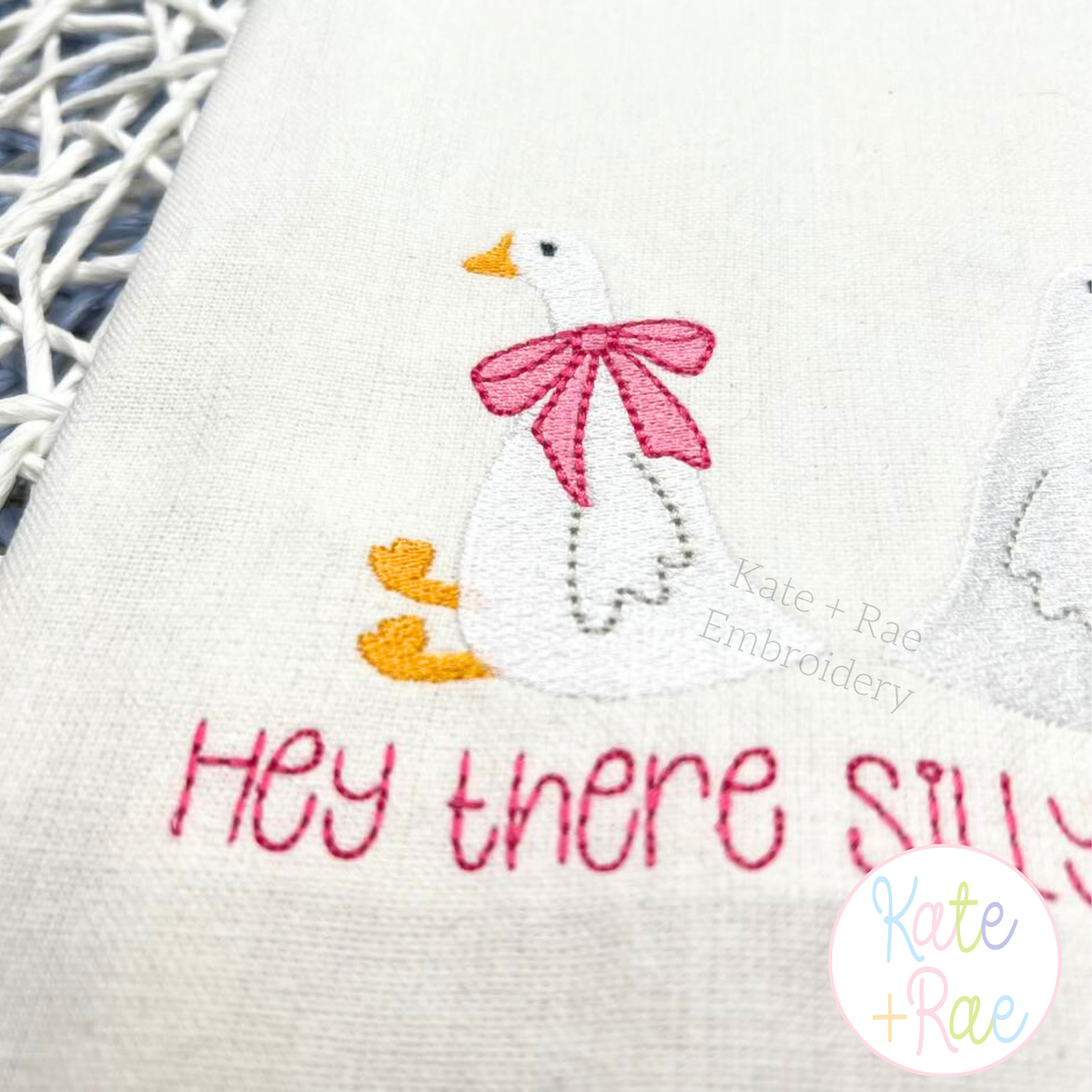 Girl Goose Mini Fill with Bow Embroidery Design: White goose with a pink bow above Hey there silly in pink on a tea towel