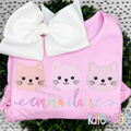 Cat Trio Sketch Stitch Embroidery Design: Three pastel sketch cat faces above the name emma claire in rainbow script on a pink shirt