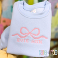 Flowy Bow Cross Stitch Embroidery Design: Pink cross stitch flowy bow above EVIE ANN on a light blue sweatshirt