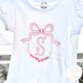 Pink heart frame with a sketch bow around a script letter S on a white shirt