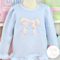 Kinley Bow Satin Stitch Applique Embroidery Design: Pastel floral bow applique on a light blue ruffled sweatshirt
