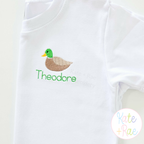 Mallard Duck Mini Fill Embroidery Design: Small mallard duck above the name Theodore in green stitched on a white shirt