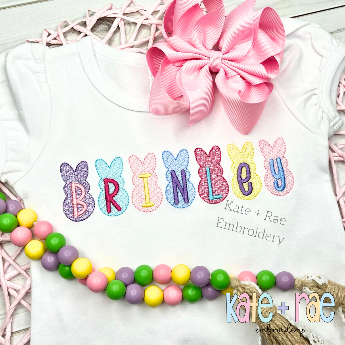 Peeps Sketch Stitch Embroidery Design: Pastel Peeps bunnies spelling BRINLEY on a white shirt with a pink bow