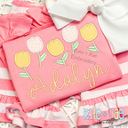 Tulip Party Satin Stitch Applique Embroidery Design: Five pastel tulip appliques above the name Adalyn in yellow script on a coral shirt