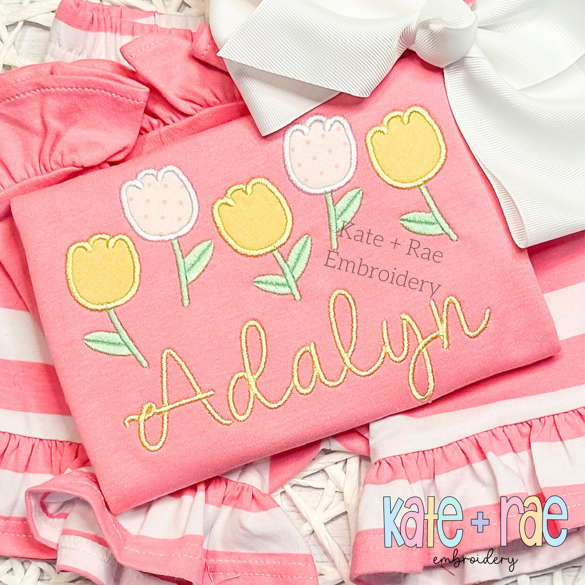 Tulip Party Satin Stitch Applique Embroidery Design: Five pastel tulip appliques above the name Adalyn in yellow script on a coral shirt
