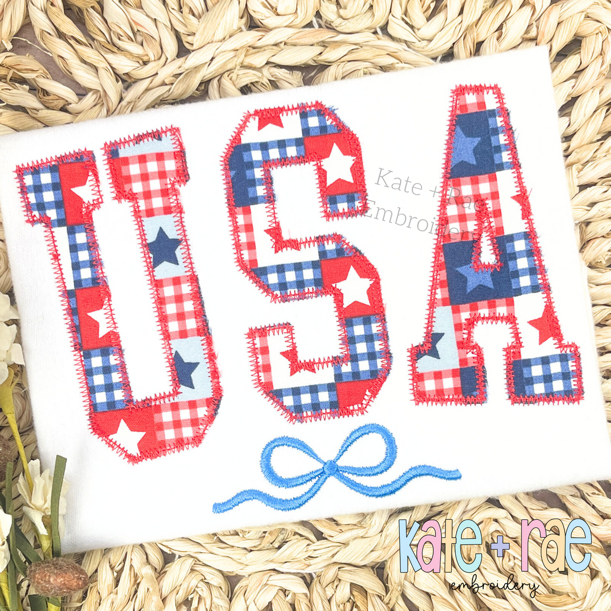 Curved USA with Bow Zigzag Stitch Applique Embroidery Design: USA in red and blue plaid star print zigzag applique letters with a blue bow on a white shirt