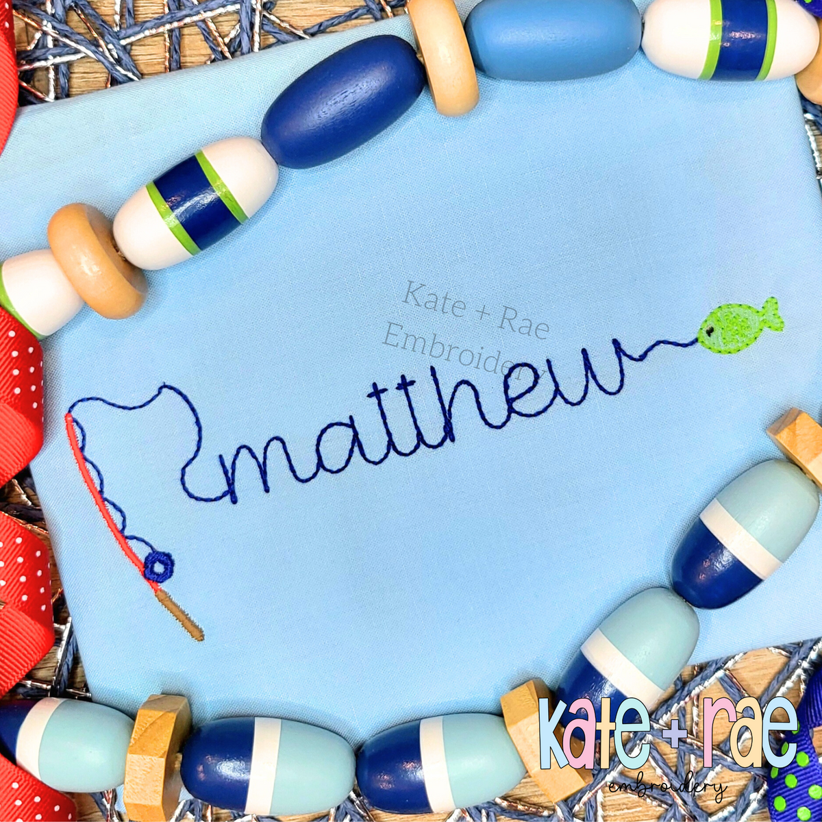 Gone Fishing Bean Stitch Embroidery Font: The name matthew in navy script with a fishing pole and green fish on a light blue shirt