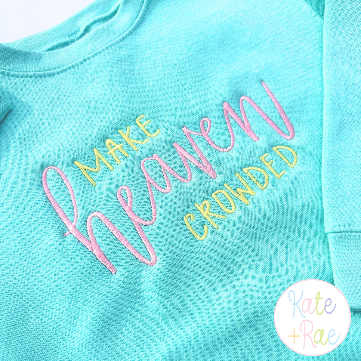Make Heaven Crowded Satin Stitch Embroidery Design: Make Heaven Crowded in pink and yellow satin lettering on an aqua sweatshirt