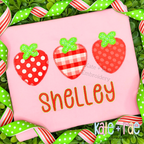 Three polka dot, gingham, and dotted strawberry appliques above the name Shelley on a pink shirt