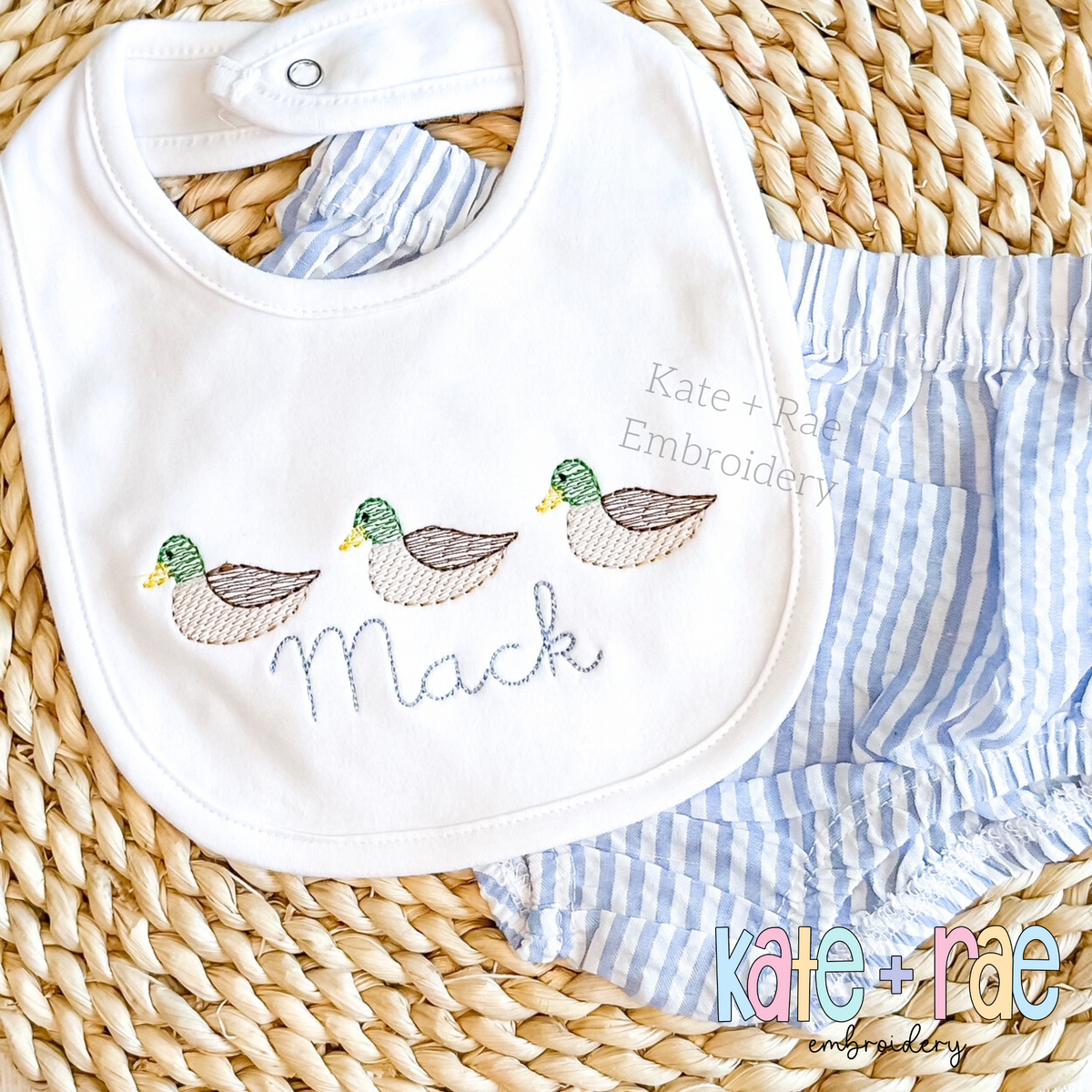 Mallard Duck Trio Sketch Stitch Embroidery Design: Three sketch stitch mallard ducks above the name Mack on a white baby bib with blue seersucker bloomers