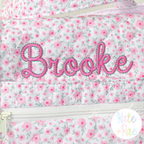 Delilah Outline Satin Stitch Embroidery Font: The name Brooke in pink outline satin script on a pink floral quilted bag
