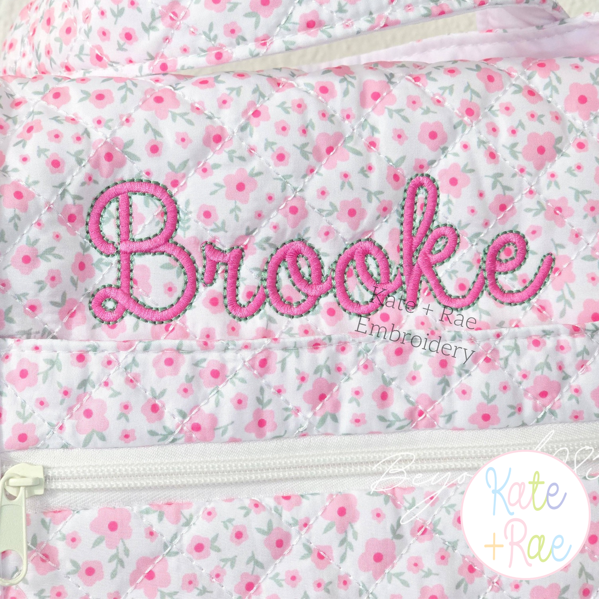 Delilah Outline Satin Stitch Embroidery Font: The name Brooke in pink outline satin script on a pink floral quilted bag