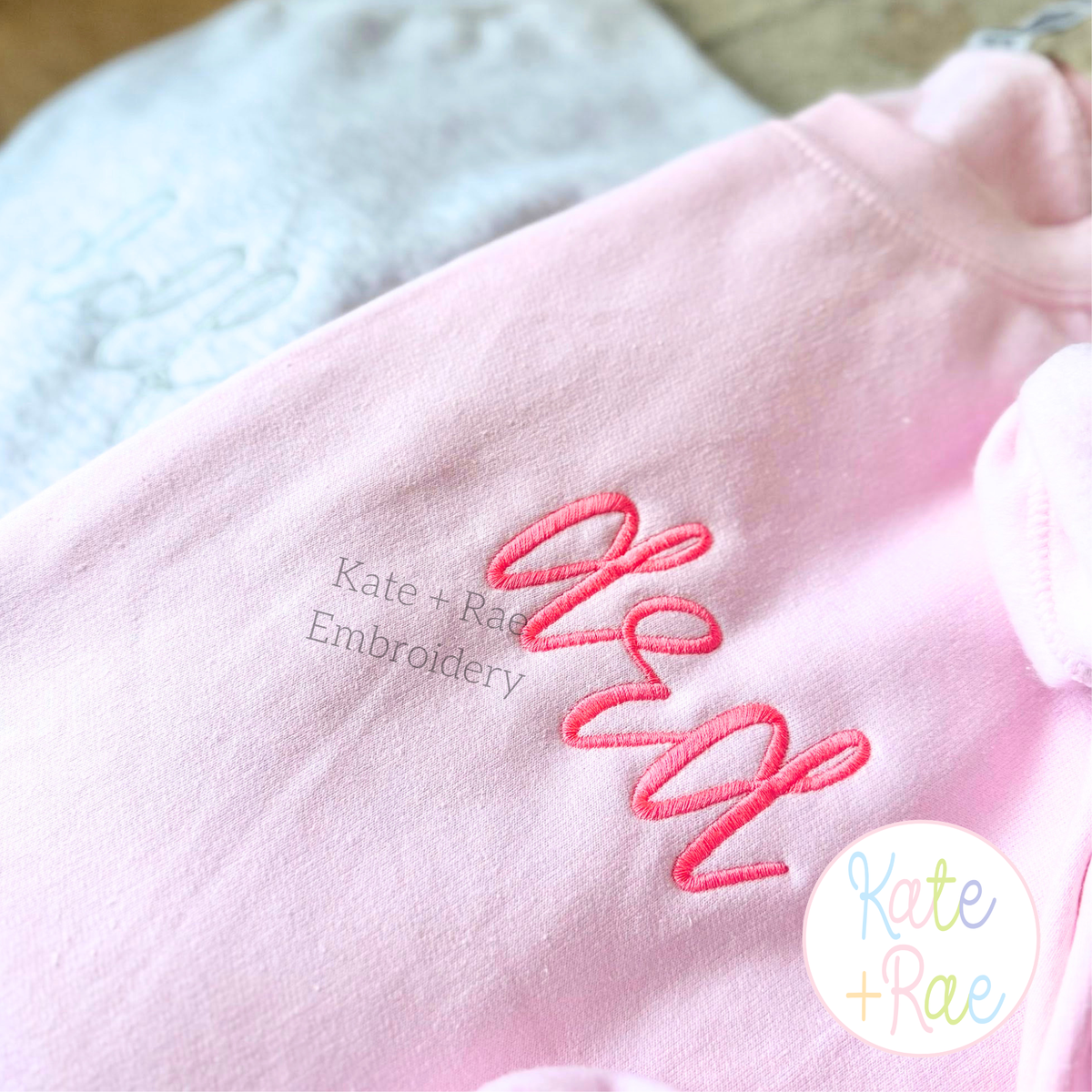 Daisy Handwritten Satin Stitch Embroidery Font: The word dad in pink handwritten satin script on a pink sweatshirt sleeve
