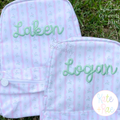 Hello Satin Stitch Embroidery Font 2.0: The names Laken and Logan in green satin script on pink striped backpacks