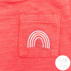 Rainbow Mini Fill Embroidery Design: Small pastel rainbow embroidered on the pocket of a coral tee