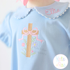 Floral Cross Pattern Fill Stitch Embroidery Design: Tan fill stitch cross with a pink bow and flowers on a light blue shirt with the name Ellie on the collar