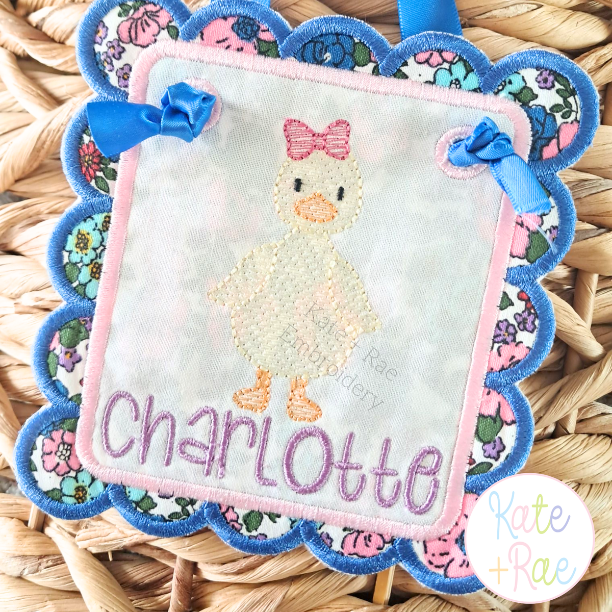 Girl Duck with Bow Sketch Stitch Embroidery Design: Scalloped banner with a sketch duck with a pink bow and the name Charlotte in purple