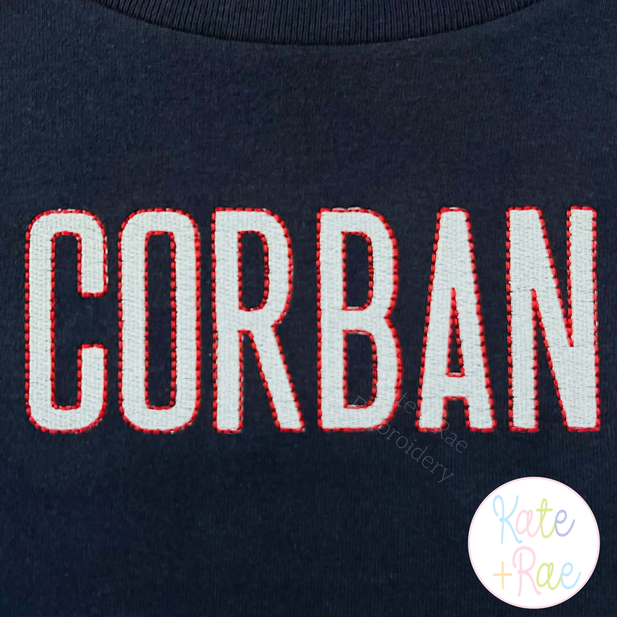 Beau Fill Stitch with Bean Stitch Border Embroidery Font: The name CORBAN in gray fill stitch letters with red bean border on a navy shirt