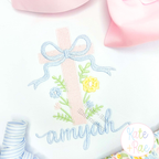 Cross Stitch Floral Cross Embroidery Design: Pink cross stitch floral cross with a blue bow above the name amyjah in blue script on white