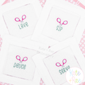 Double Tennis Racket Mini Fill Embroidery Design: Crossed pink tennis rackets above the words Love, Sip, Deuce, and Serve stitched on white cocktail napkins