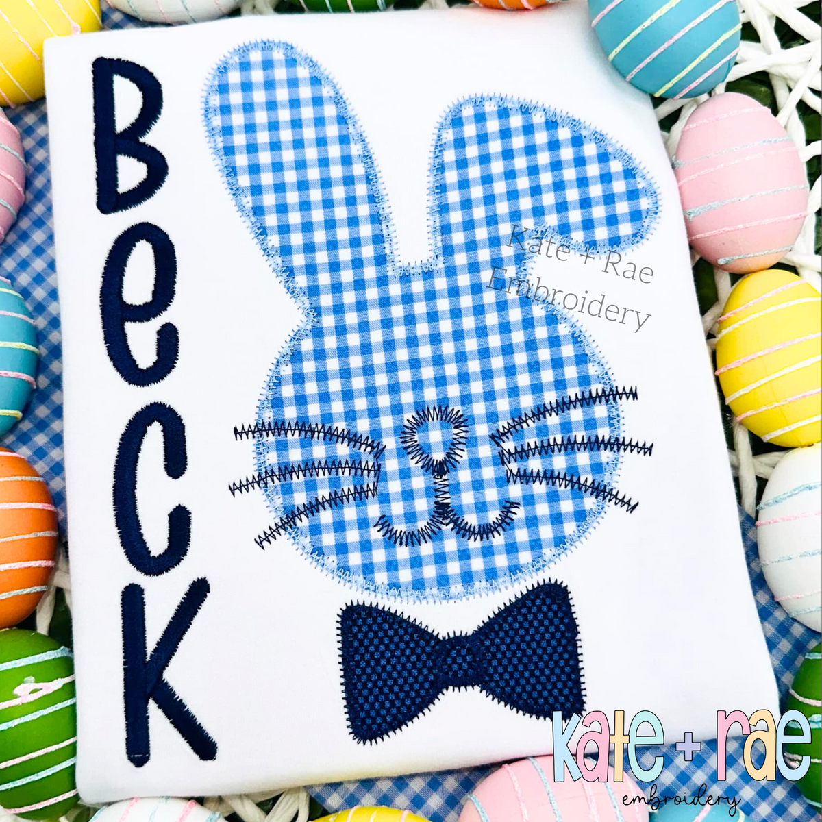Boys Easter Bunny with Bow Tie Zigzag Stitch Applique Embroidery Design: Blue gingham zigzag applique bunny with a navy bow tie beside the name Beck in navy letters on a white shirt