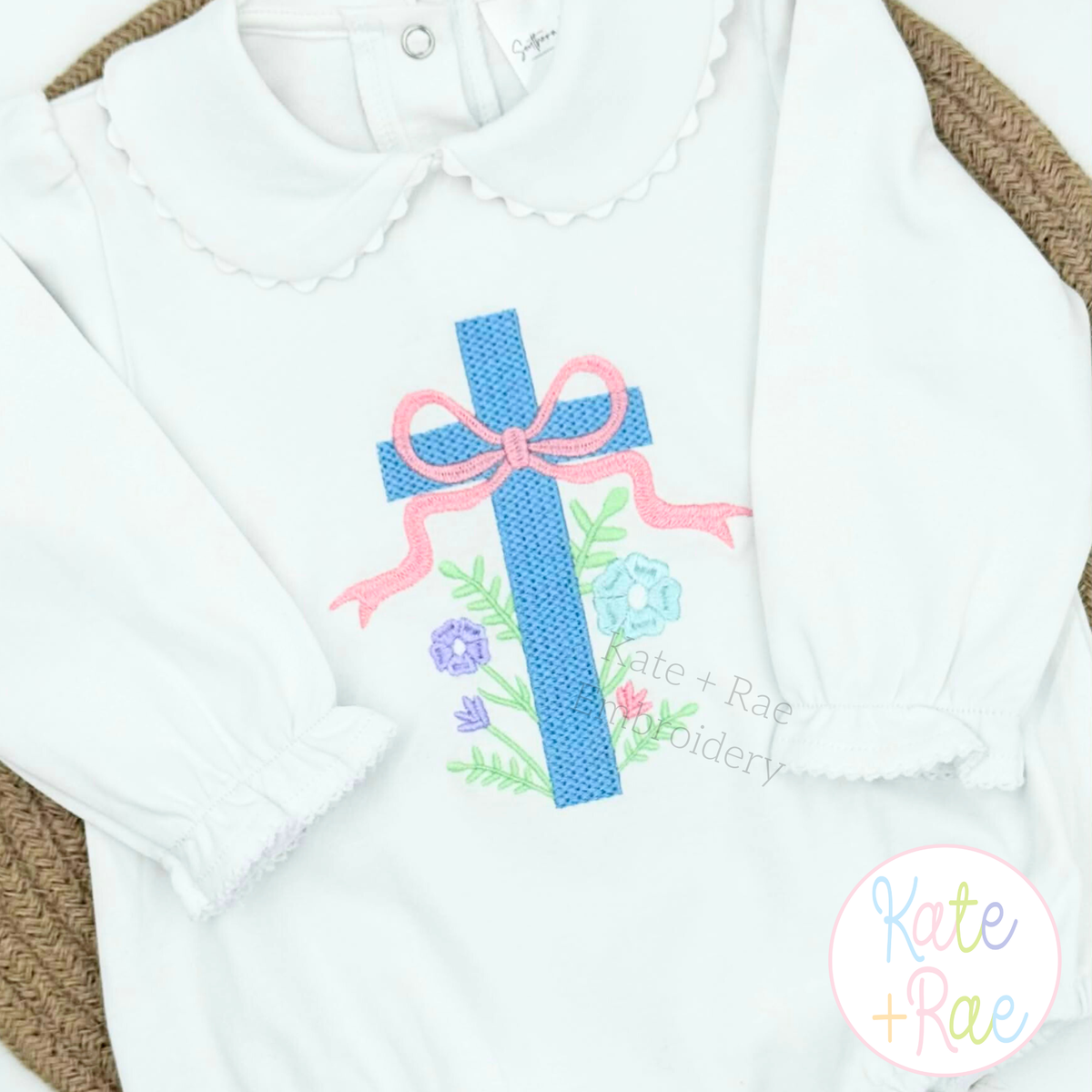 Floral Cross Pattern Fill Stitch Embroidery Design: Blue cross with a pink bow and flowers on a white ruffle collar shirt
