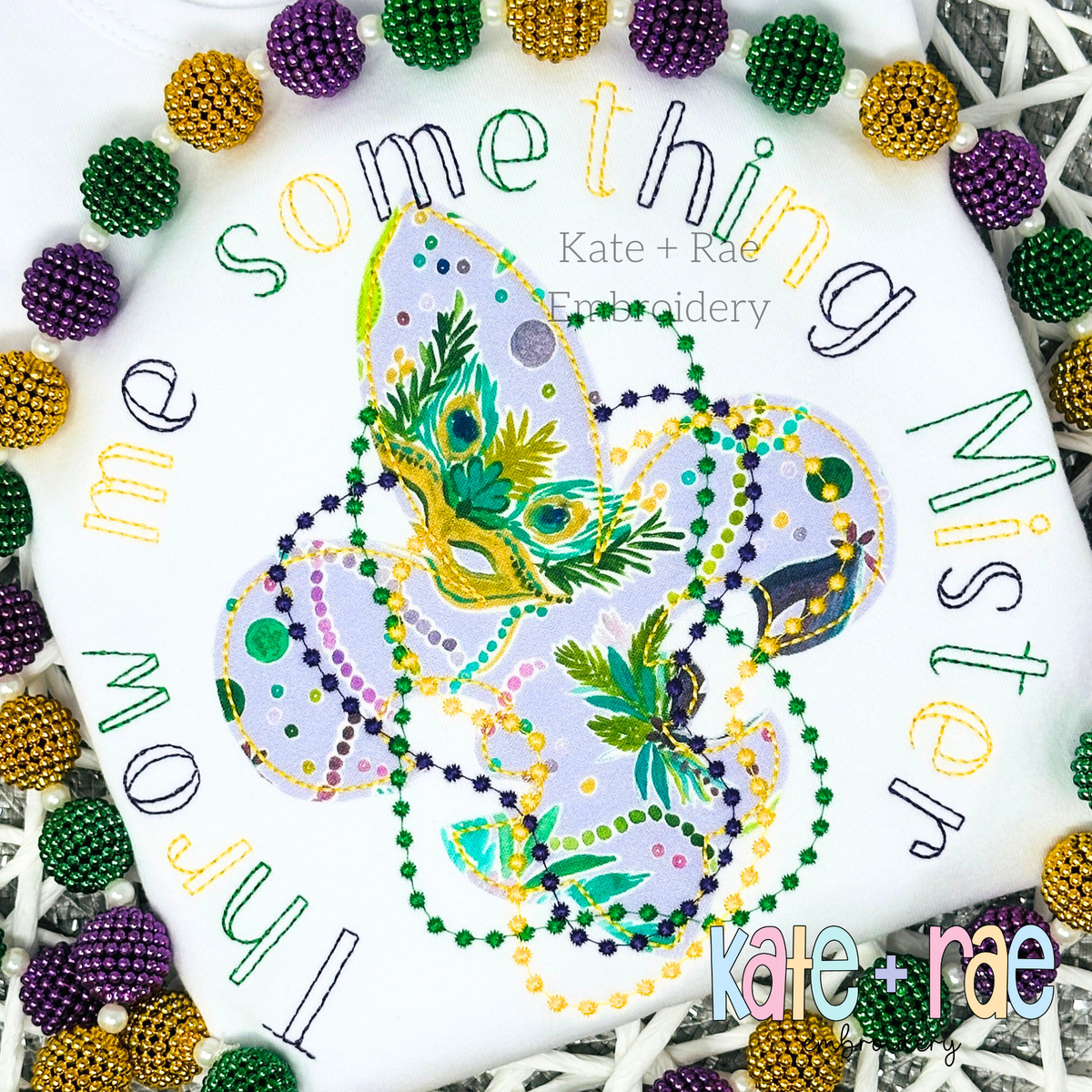 Charlie Bean Stitch Embroidery Font: The words throw me something Mister in multicolored letters around Mardi Gras beads and a mask