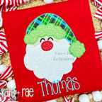 Santa Claus Zigzag Applique Embroidery Design: Santa face applique with a plaid hat and green trim above the name Thomas in blue on a red shirt