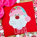 Santa Claus Zigzag Applique Embroidery Design: Santa face applique with a floral hat and red glitter nose above the name Liliana in pink on a red shirt