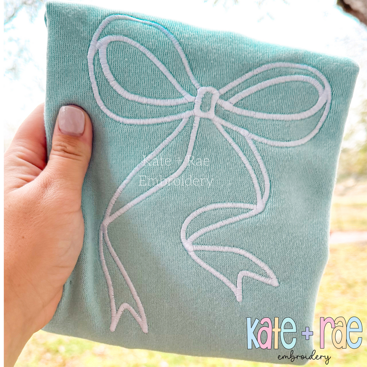 Sadie Bow Satin Stitch Applique Embroidery Design: White outline Sadie bow satin stitch on a sage green sweatshirt