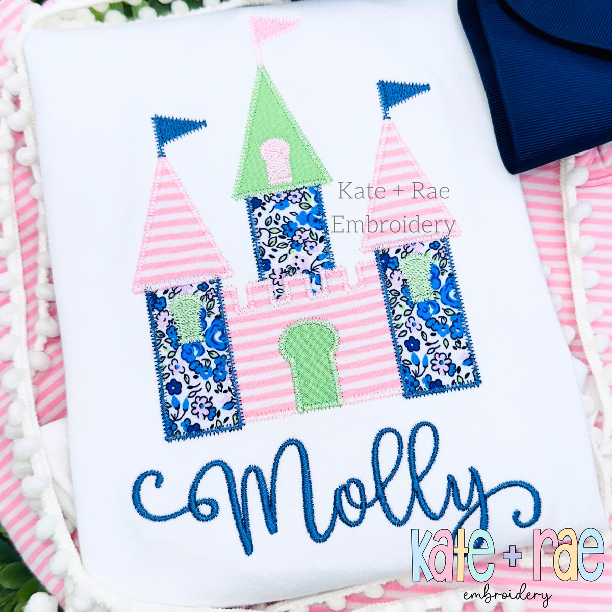 Princess Castle Zigzag Stitch Applique Embroidery Design: Princess castle applique in pink striped, green, and navy floral fabrics above the name Molly in blue script on a white shirt