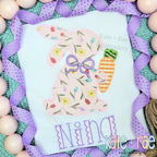 Girl's Easter Bunny with Carrot and Bow Zigzag Stitch Applique Embroidery Design: Pink floral bunny applique with a purple bow and gingham carrot above the name Nina in purple on a white shirt