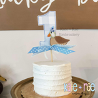 Mallard Duck Bean Stitch Applique Cake Topper Add On Embroidery Design: Blue gingham number 1 cake topper with a small duck applique and blue polka dot ribbon on a white cake