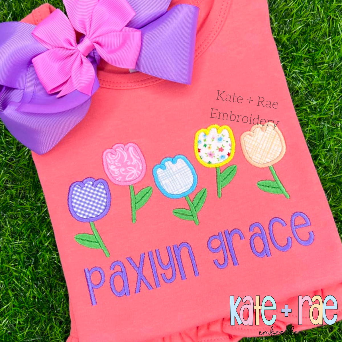 Tulip Party Satin Stitch Applique Embroidery Design: Five patterned tulip appliques above the name paxlyn grace in purple on a coral shirt