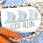 Boy's Easter Bunny with Carrots Trio Sketch Stitch Embroidery Design: Three light blue sketch bunnies holding carrots above the name Luca Allen in navy on a white shirt