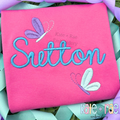 The name Sutton in aqua satin script with butterflies on a hot pink shirt