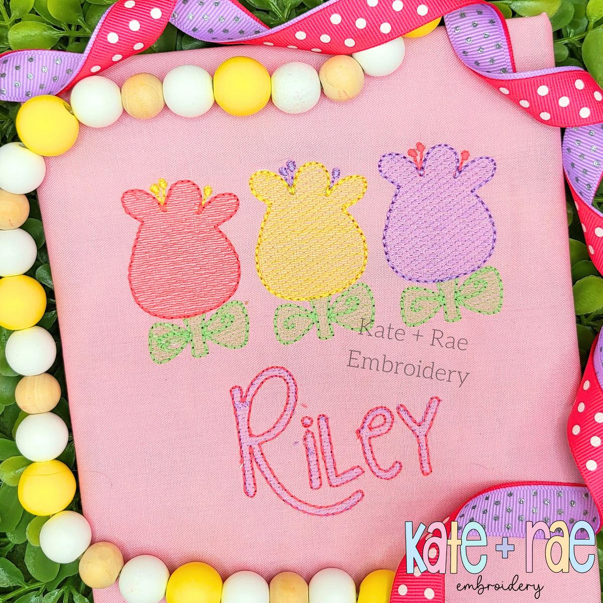 Fun Tulip Trio Sketch Stitch Embroidery Design: Three pink, yellow, and purple sketch tulips with green leaves above the name Riley in pink on a pink shirt