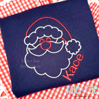 Santa Claus Satin Stitch Applique Embroidery Font: Red and white outline Santa face with the name Kace in red script on a navy shirt