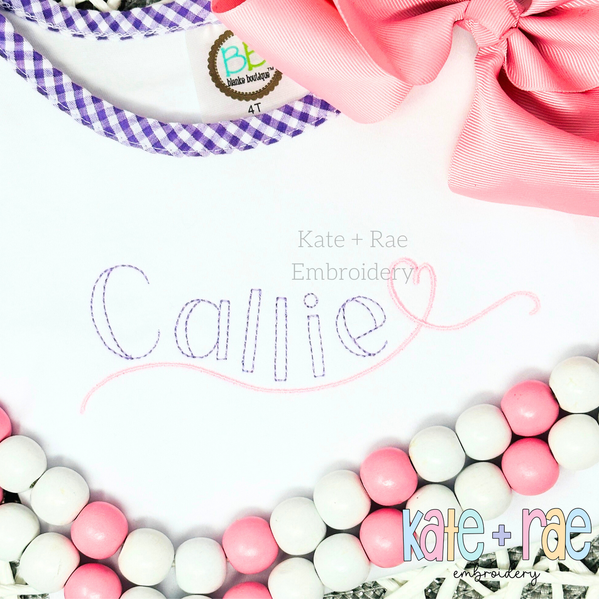 Charlie Bean Stitch Embroidery Font: The name Callie in lavender bean stitch letters with a pink heart on a white bib