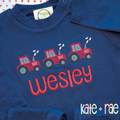 Heart Tractor Trio Sketch Stitch Embroidery Design: Three red sketch stitch tractors with smoke above the name Wesley in red on a navy shirt