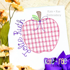 Girl's Plaid Filled Apple Embroidery Design: Pink plaid apple with a purple bow beside the name Jolie Ruth in purple script on a white shirt
